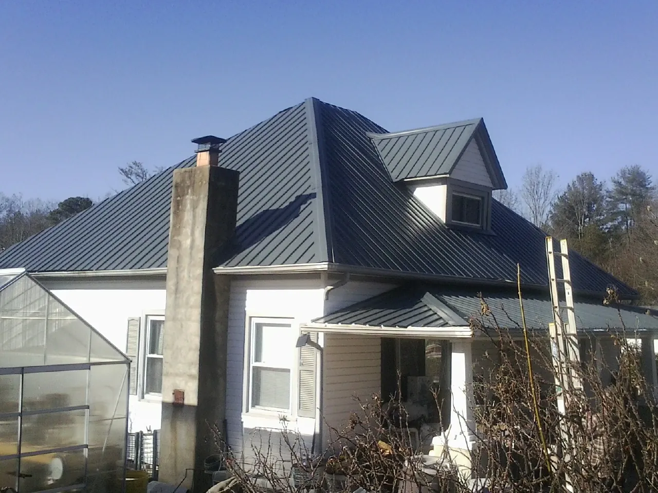 Dark blue standing seam metal roof on a white farmhouse with dormer — Slate & Tile Roof Repair by Roofing Brothers in Canyon