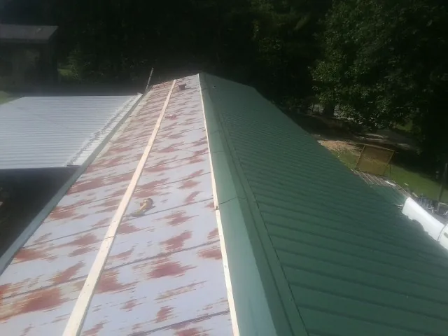 Old rusted panels beside newly installed green metal roofing — Wind Damage Roof Repair by Roofing Brothers in Canyon