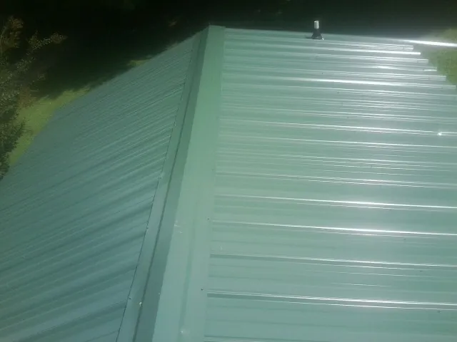 New green metal panels meeting at the ridge of a roof — Flat Roof Repair work by our crew in Canyon