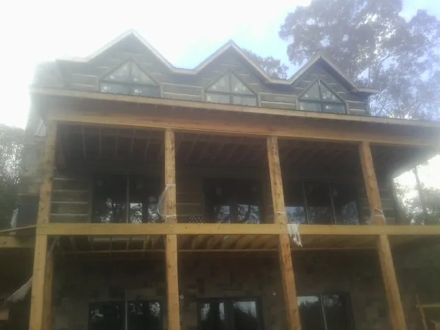 Dormers and porch framing on a large log home under construction — Roof Coating work by our crew in Canyon