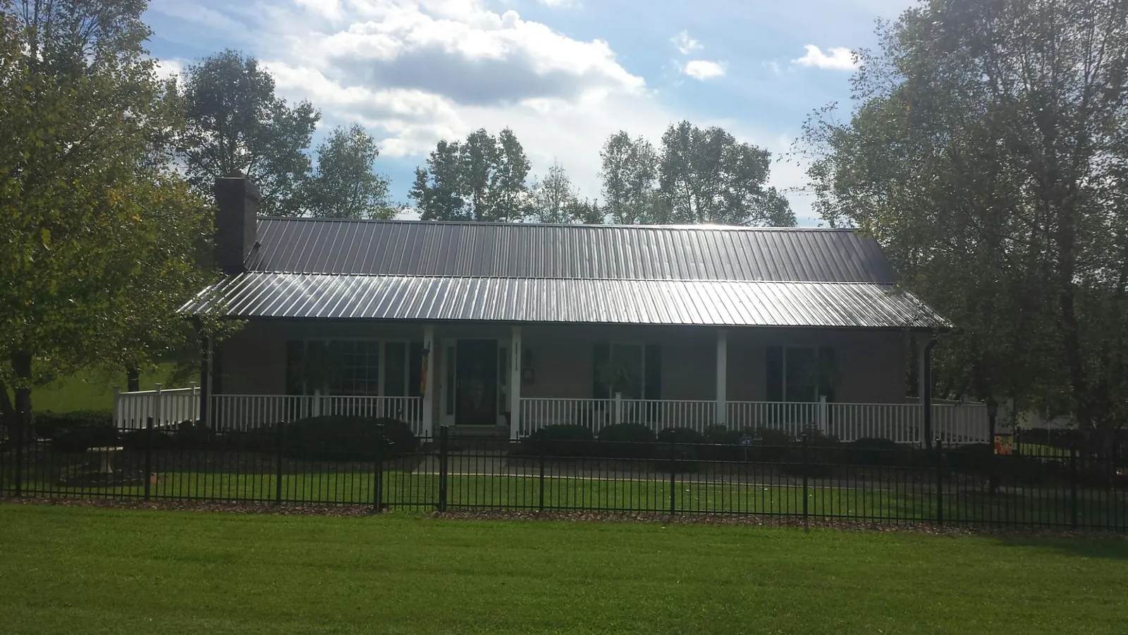 Gray metal roof on a brick ranch with a full width front porch — Gutter Guard Installation work by our crew in Canyon