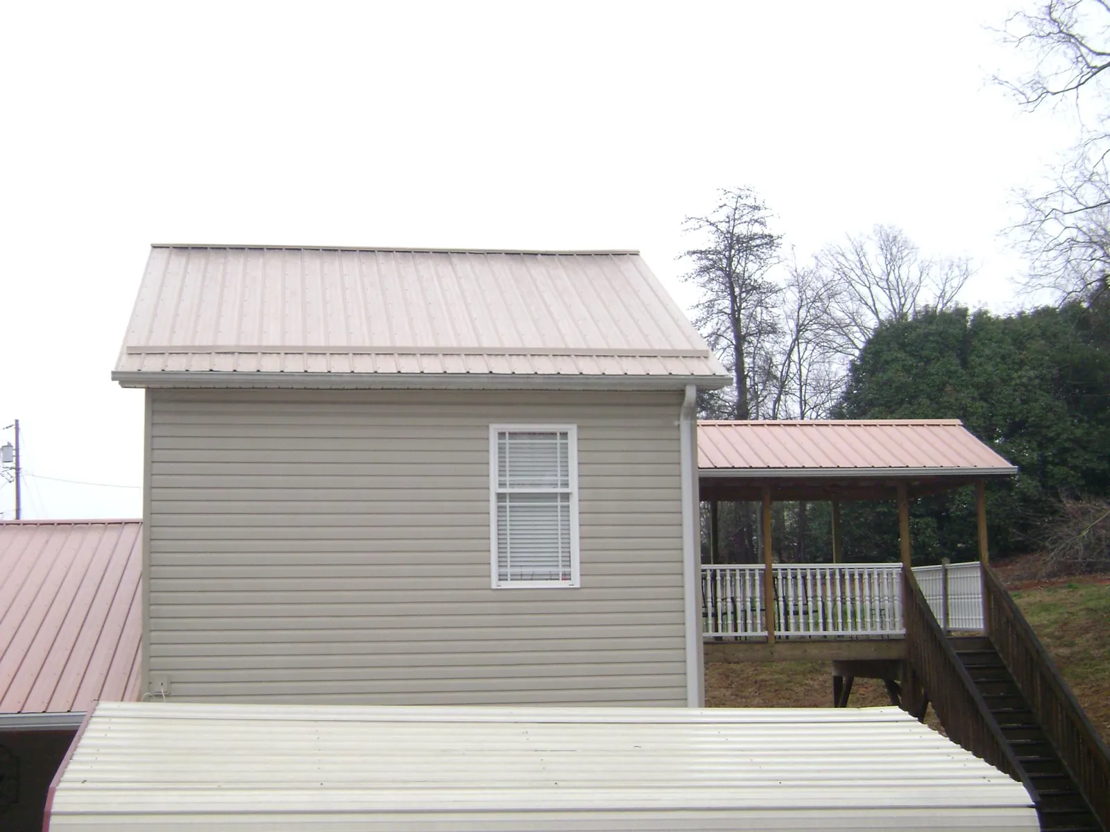 Tan metal roofs on a two story addition and attached porch, from a Roof Replacement job in Canyon