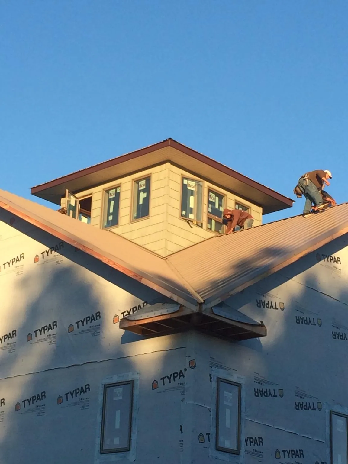 Roofers working around a rooftop cupola on a new metal roof at sunset — Roof Waterproofing in Canyon by Roofing Brothers